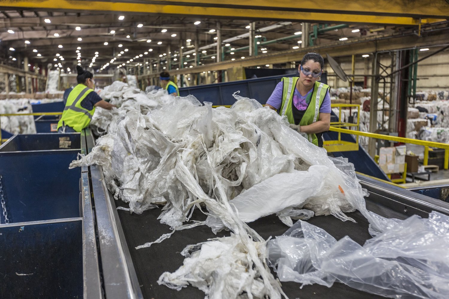 Workers sorting flexible plastic film on a conveyor at a recycling facility