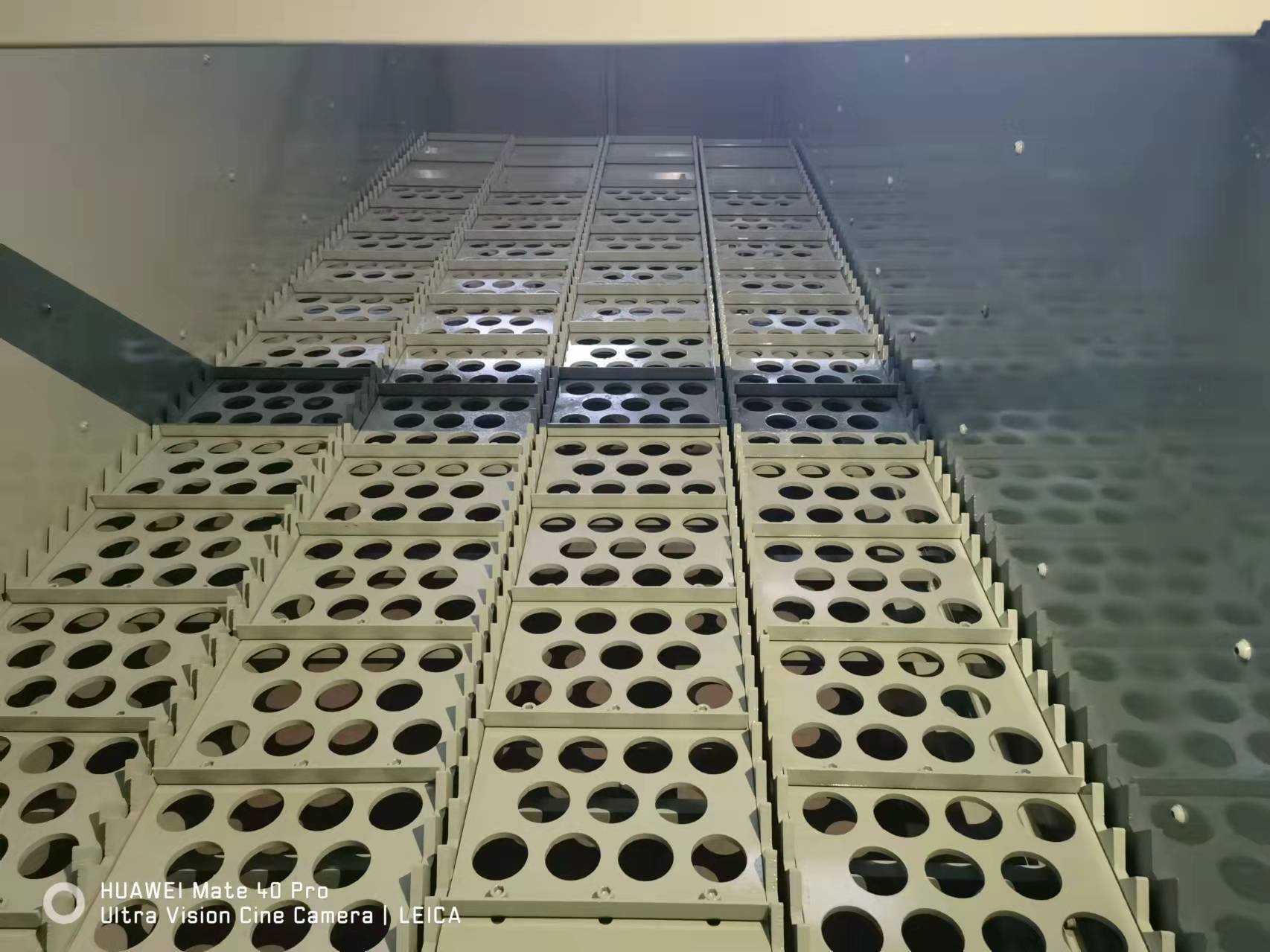 Photograph looking along parallel perforated paddles inside a ballistic separator